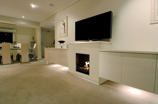 Modern living room with a television mounted on the wall above a fireplace.