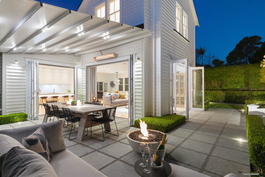 Modern outdoor patio area with seating, fire pit, and house in the background