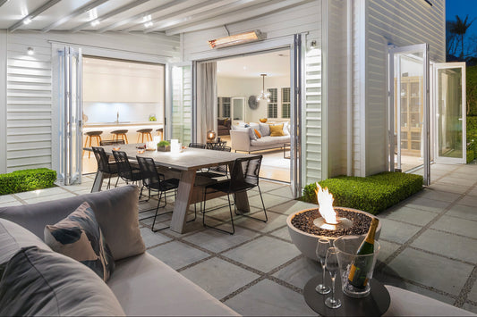 Modern outdoor patio area with seating, fire pit, and house in the background