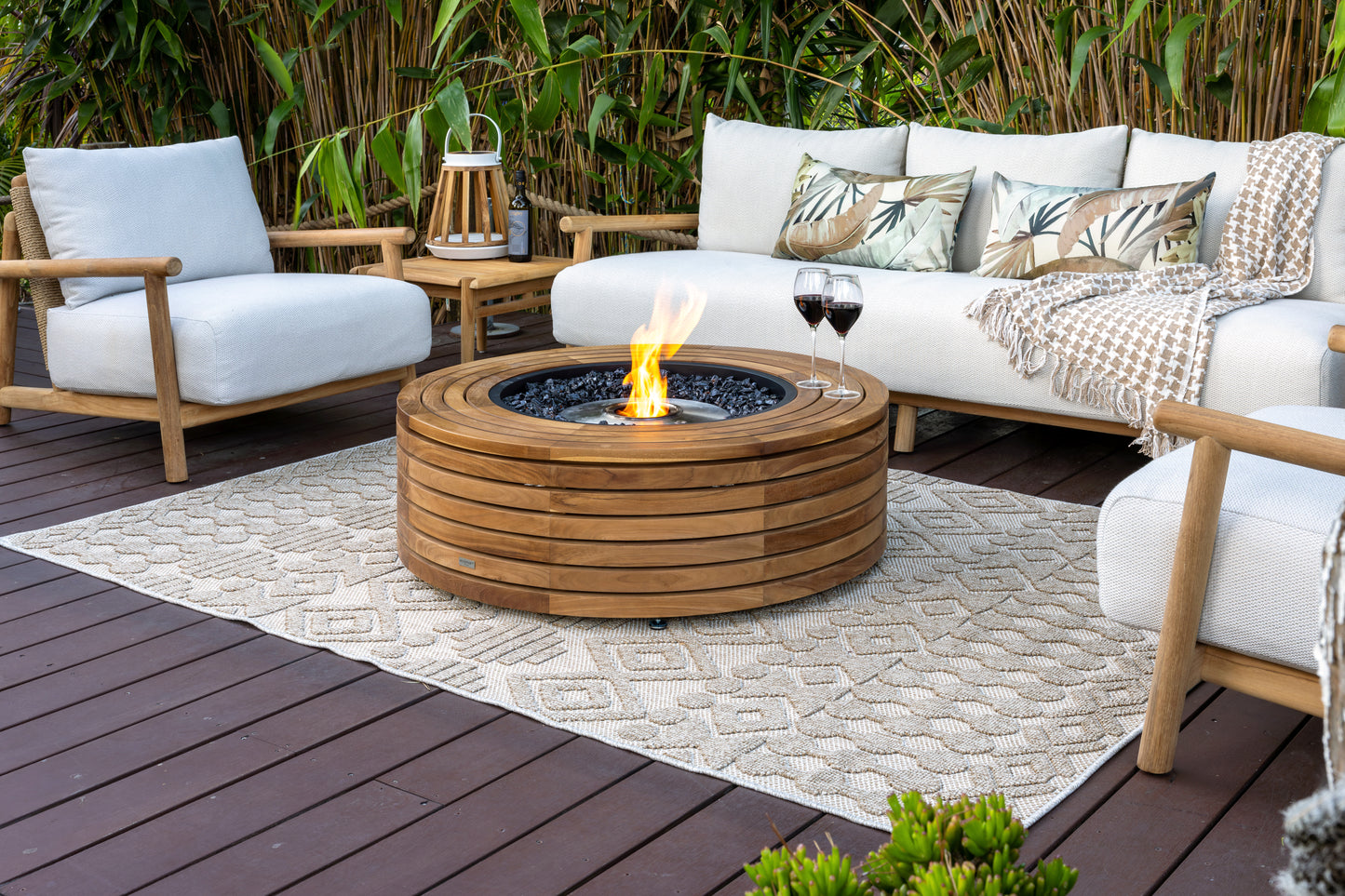 Outdoor patio with wooden fire pit, chairs, and a sofa with decorative pillows.