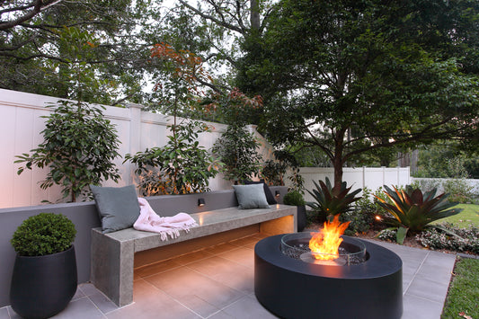 Outdoor patio with a fire pit, bench, and potted plants