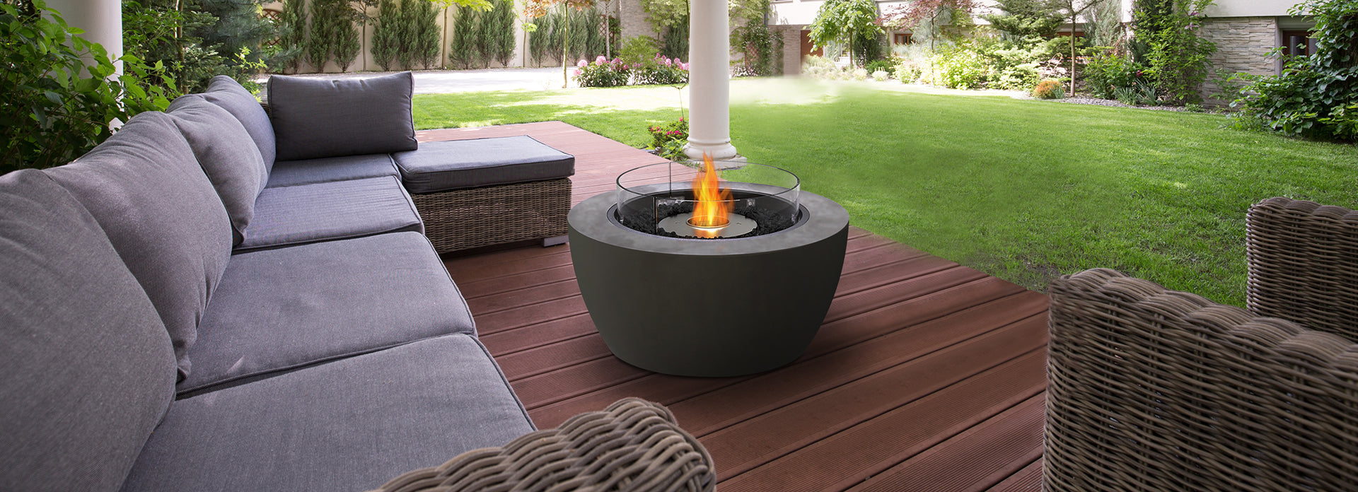 Outdoor patio setting with a gray sectional sofa and bioethanol fire pit table.