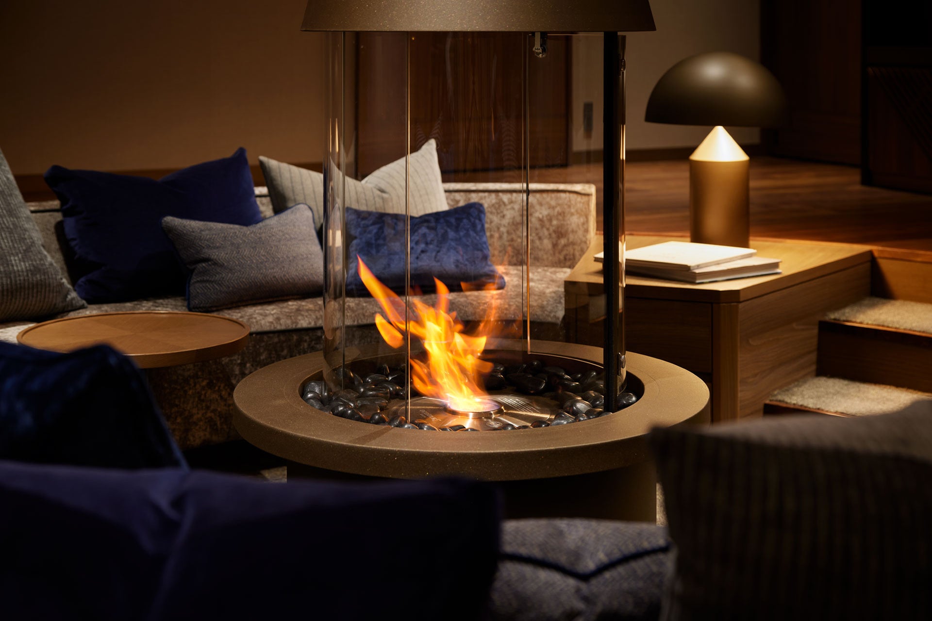 Modern indoor fire pit with flames in a cozy living room setting.