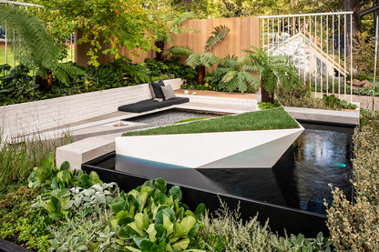 Modern garden with a water feature, seating area, and lush greenery.