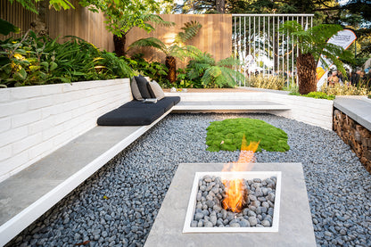 Outdoor setting with a fire pit, seating area, and greenery.