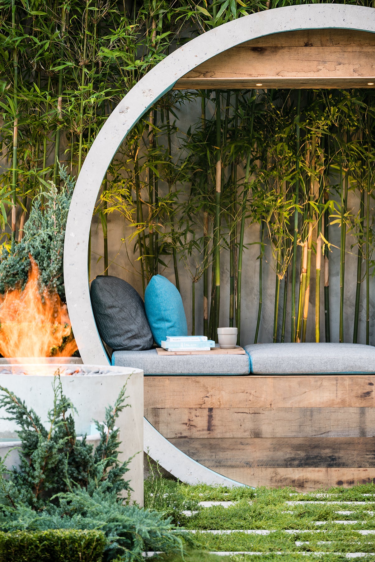 Outdoor seating area with a fire pit, cushions, and a circular wooden structure.
