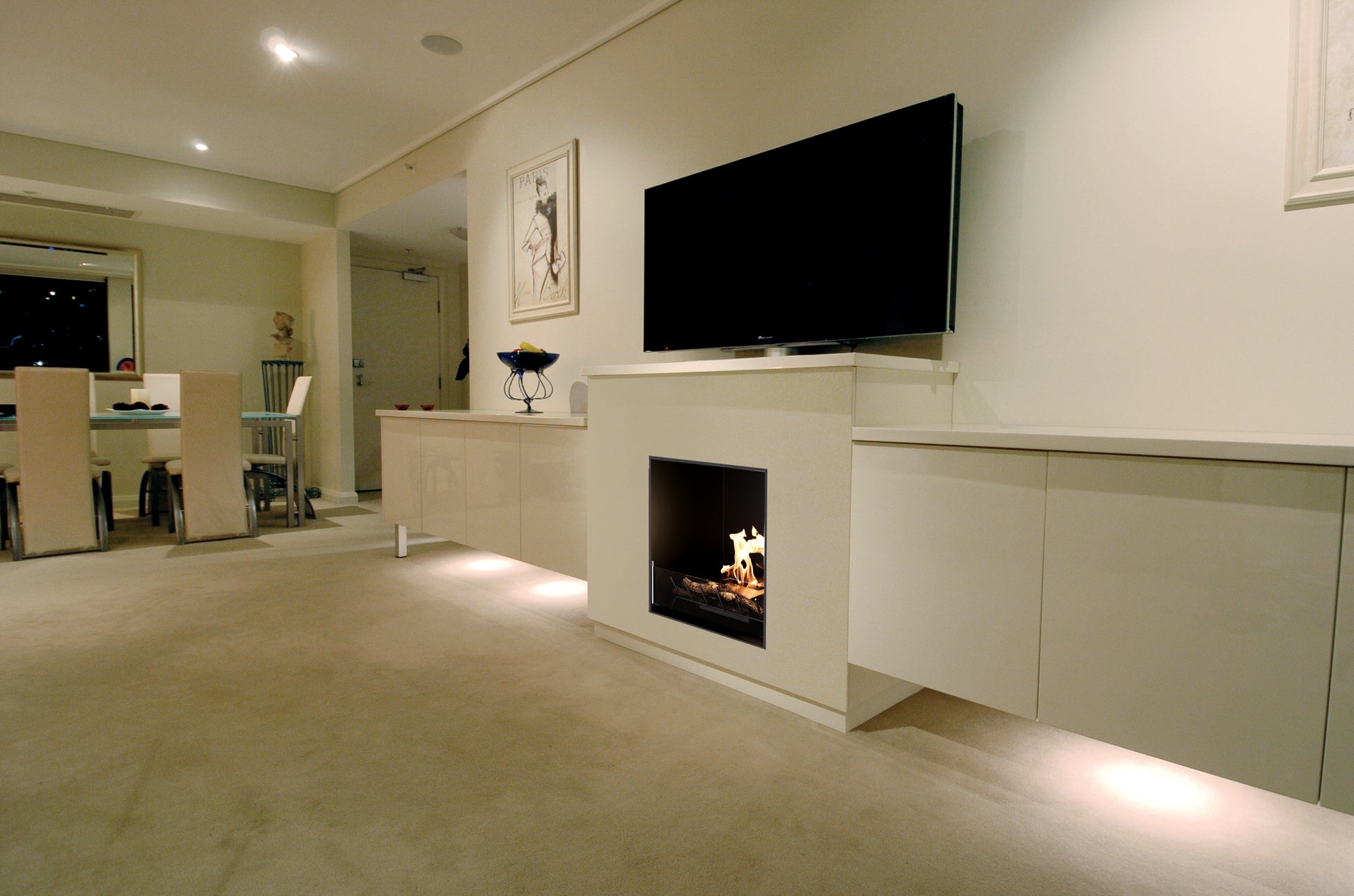 Modern living room with a television mounted on the wall above a fireplace.