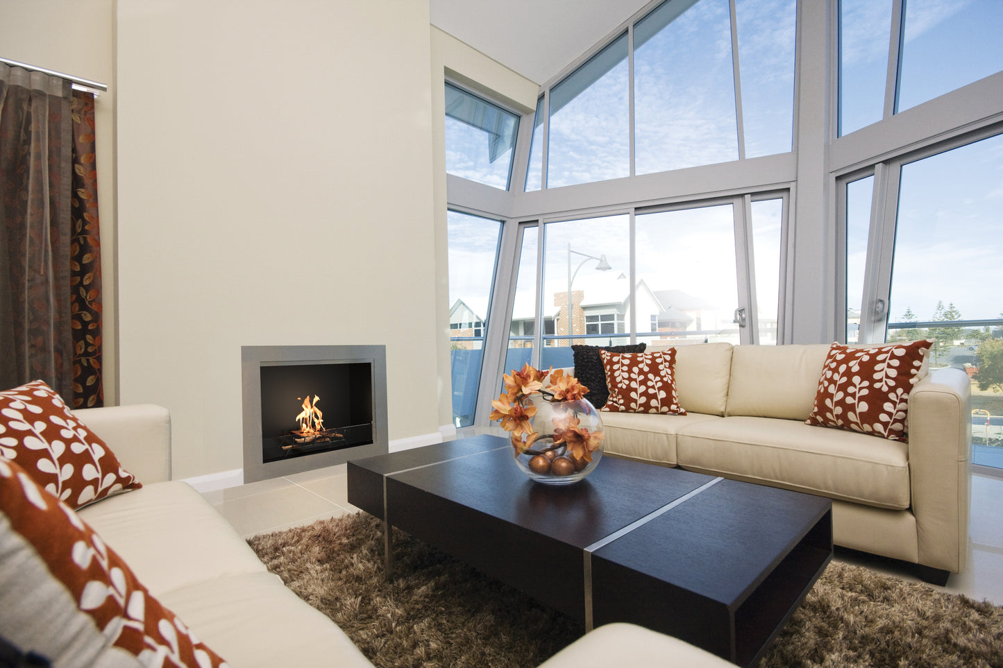 Modern living room with beige sofa, coffee table, and fireplace in a well-lit room.
