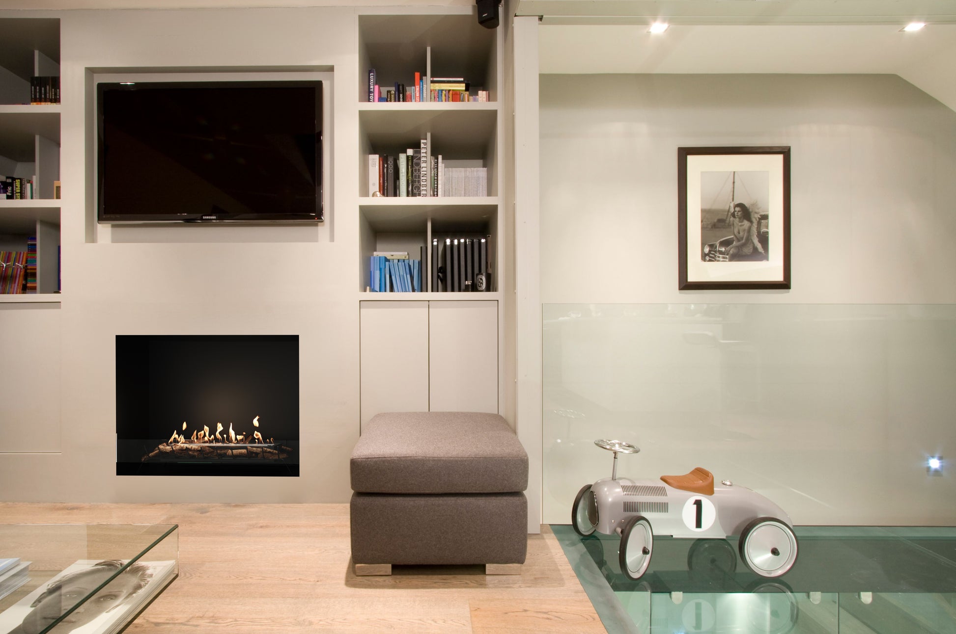 Modern living room with fireplace, bookshelf, and toy car.