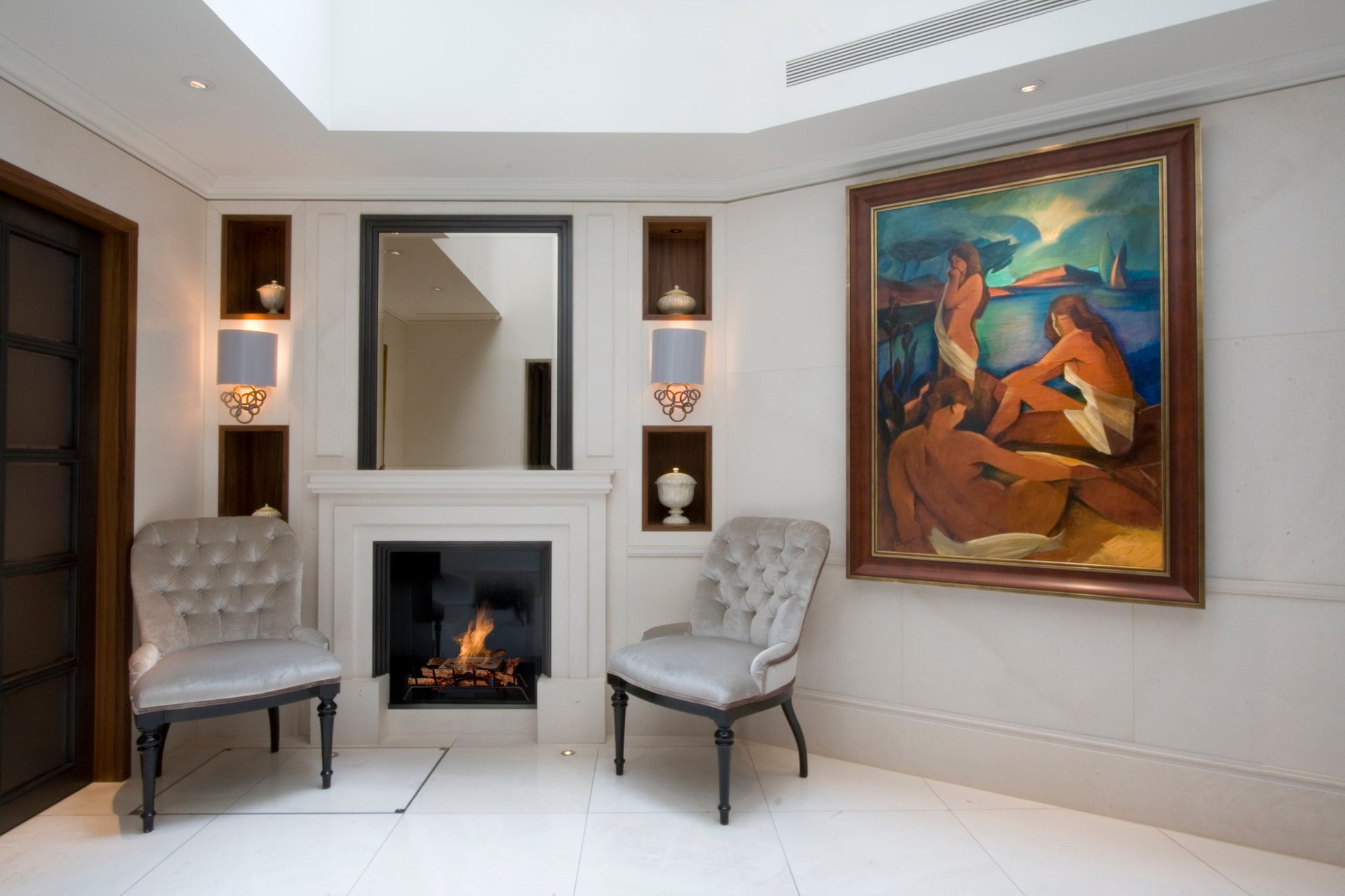 Living room with fireplace, chairs, and a large painting on the wall.