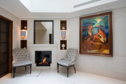 Living room with fireplace, chairs, and a large painting on the wall.