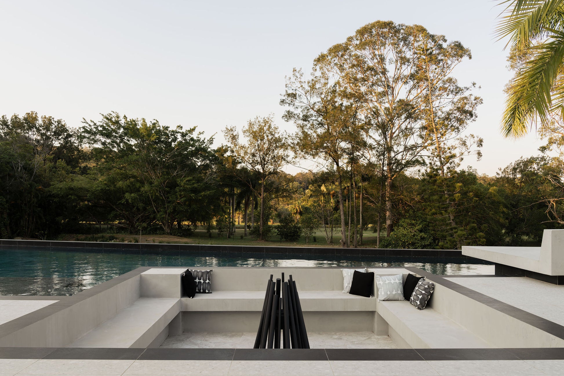 Modern outdoor seating area with a pool and trees in the background