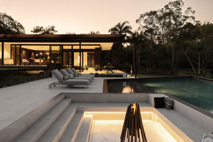 Modern outdoor living area with pool and fire pit at dusk