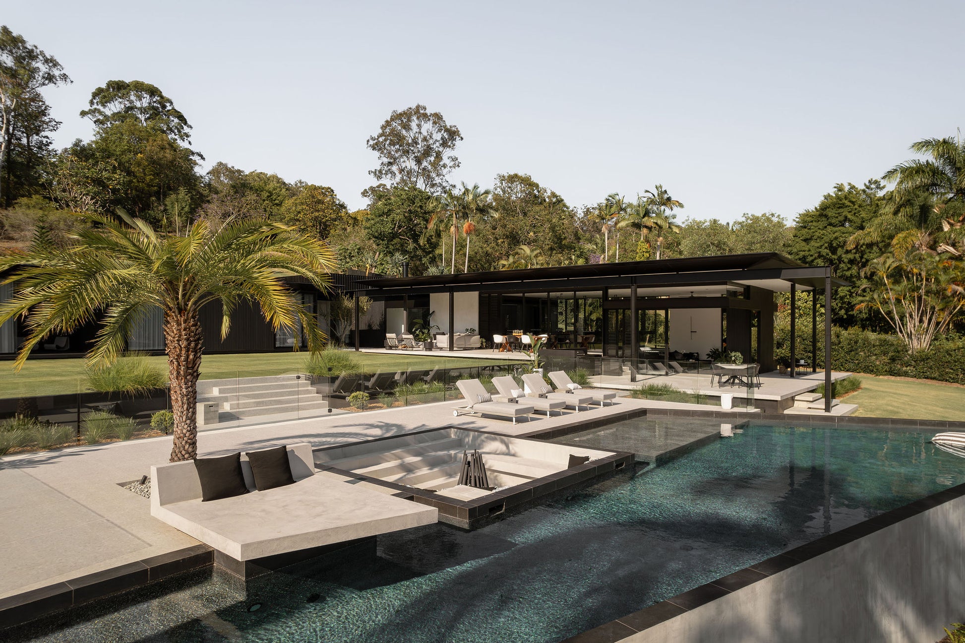 Modern outdoor living area with pool, lounge chairs, and covered pavilion.