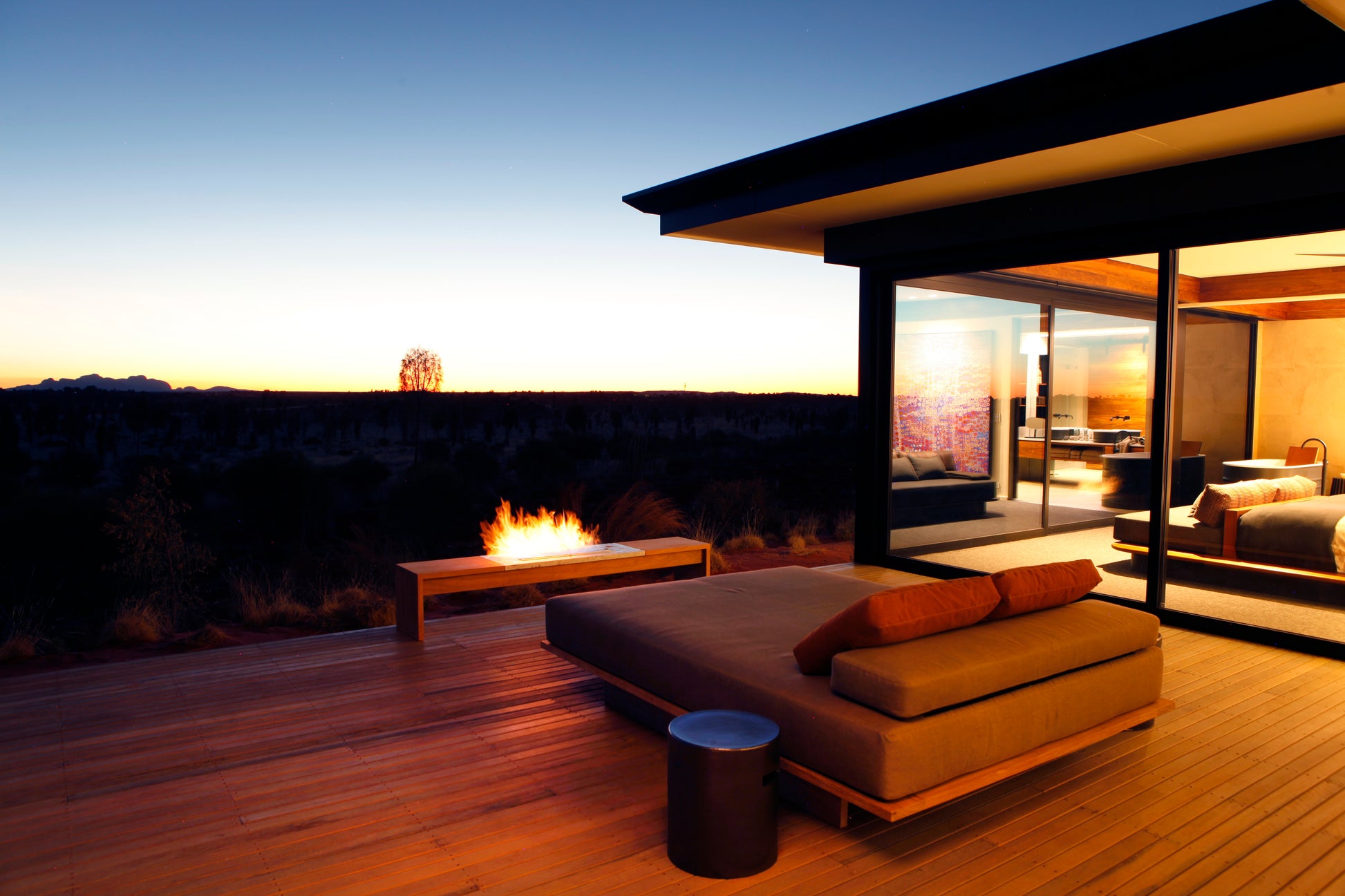 Modern outdoor living space with a fire pit and lounge area at dusk.