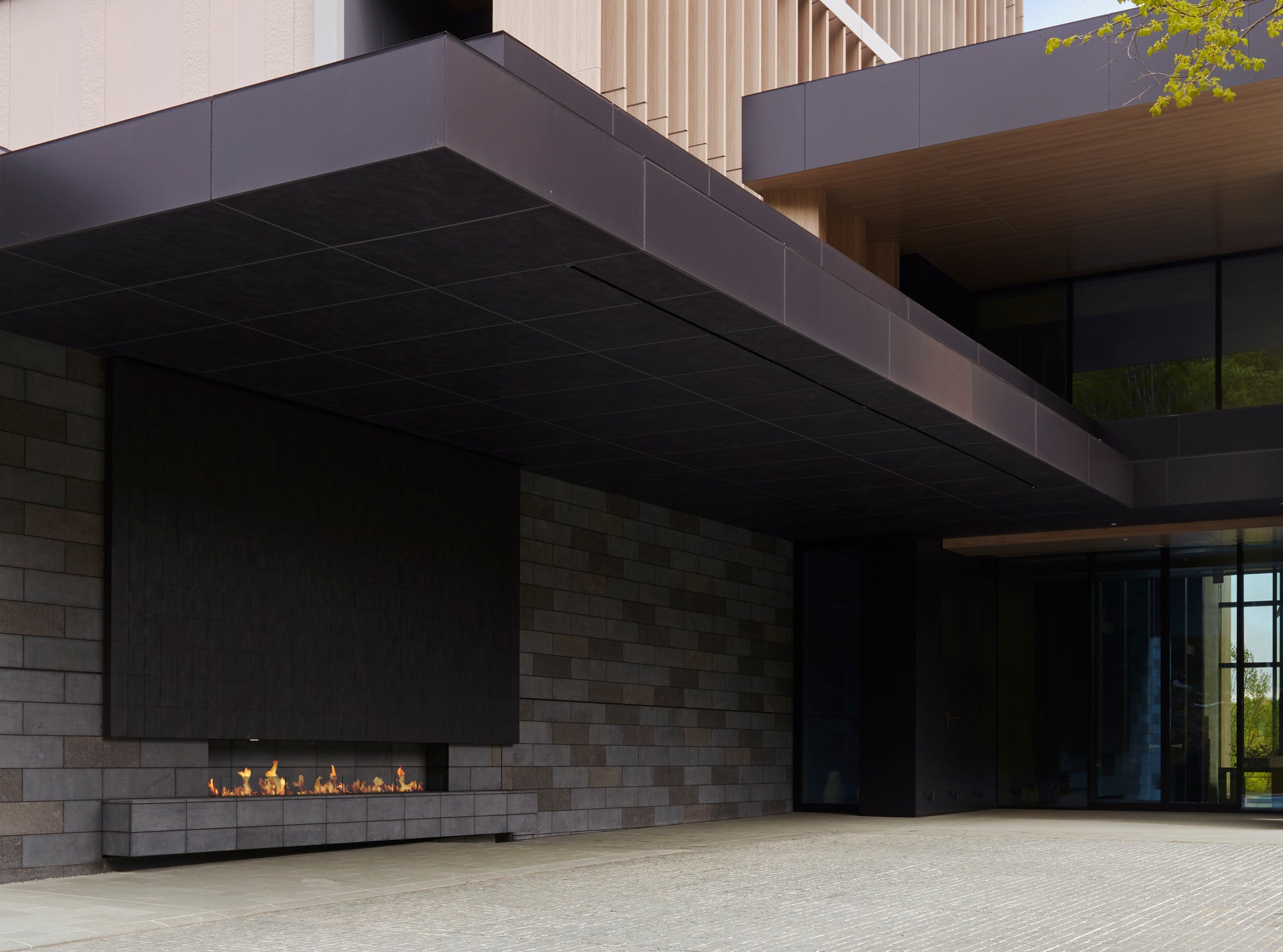 Modern outdoor fireplace with stone wall and glass doors in the background