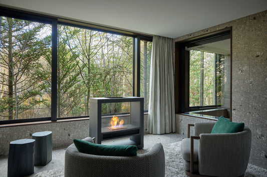 Modern living room with a fireplace and large windows overlooking trees