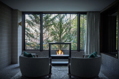 Modern living room with a fireplace and large windows overlooking trees