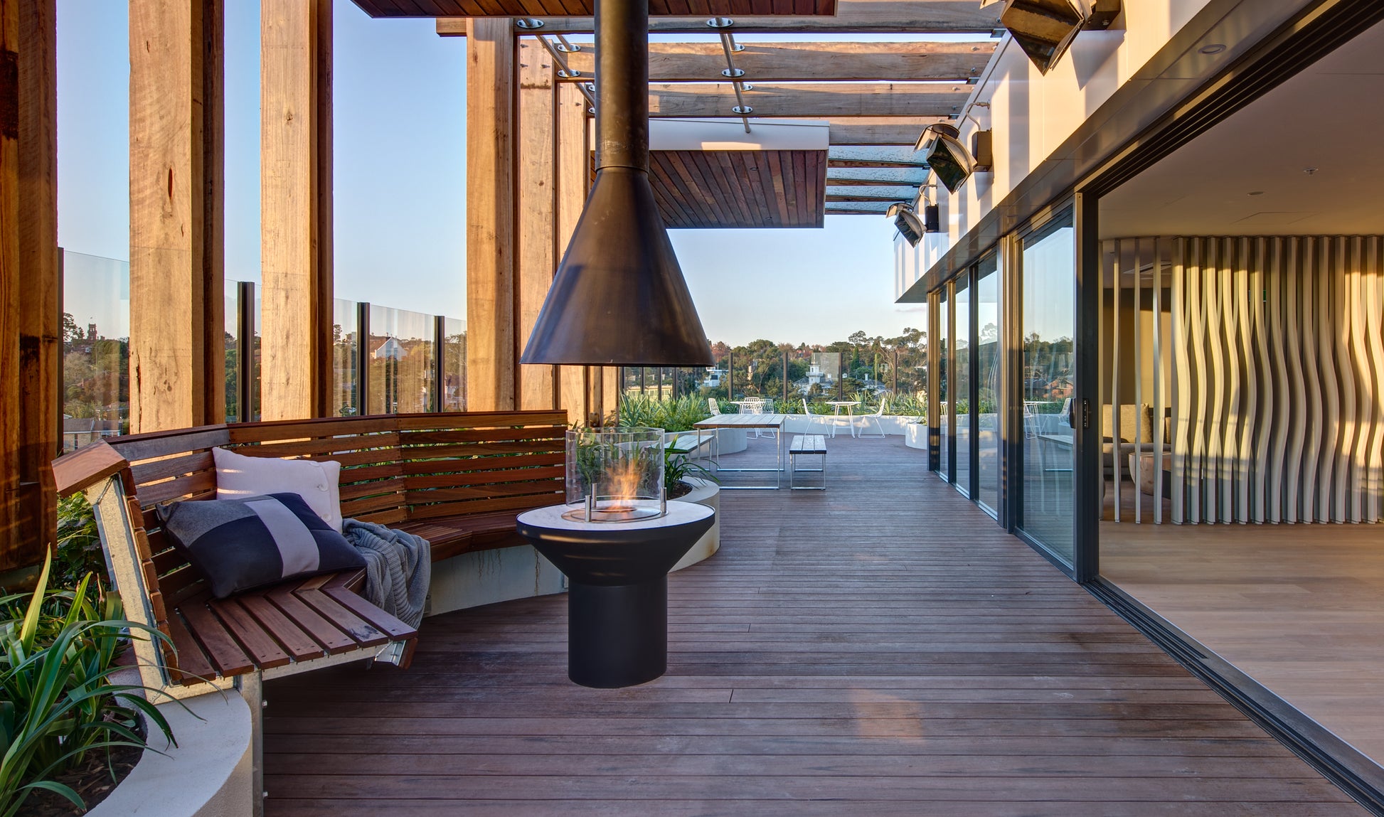 Modern outdoor patio with wooden deck, seating area, and water view
