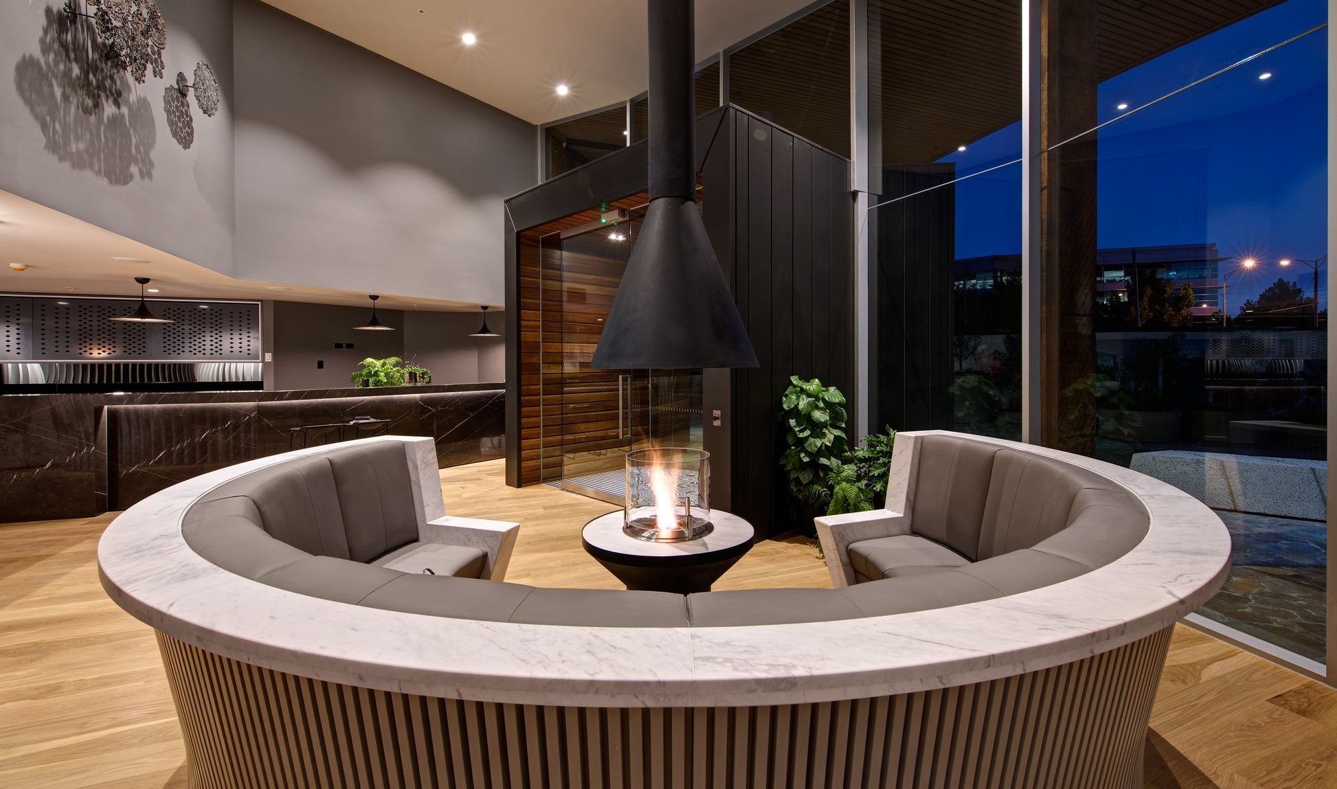 Modern indoor living space with a circular sofa and fire pit.