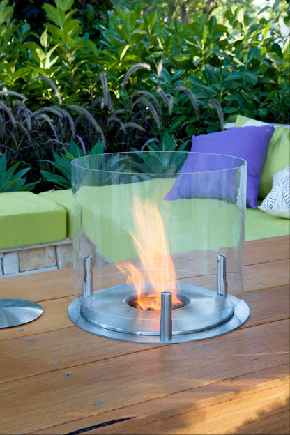 Outdoor fire pit on a wooden deck with green and purple cushions in the background