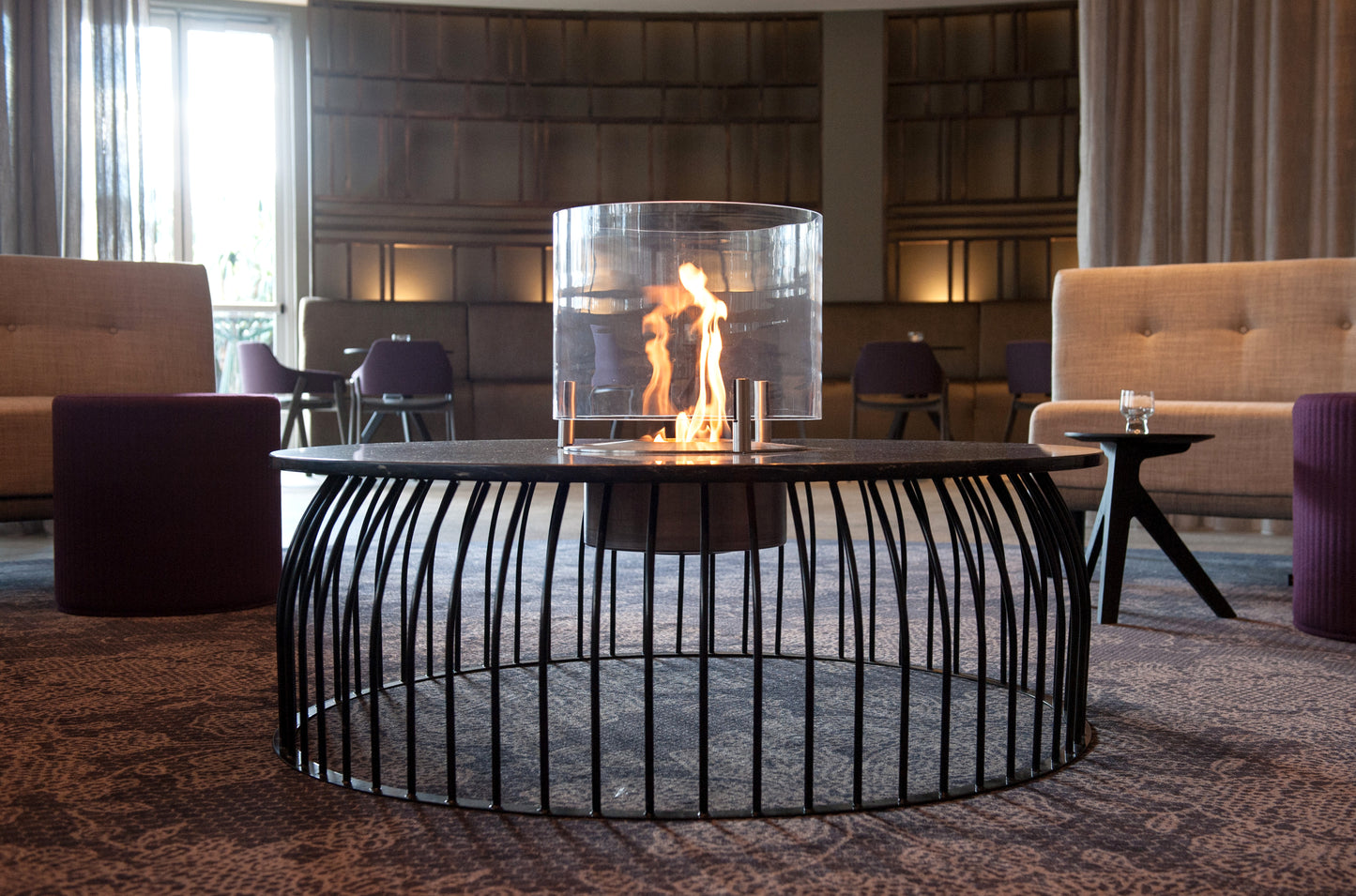 Modern indoor fire pit with flames in a stylish room with furniture and decor.