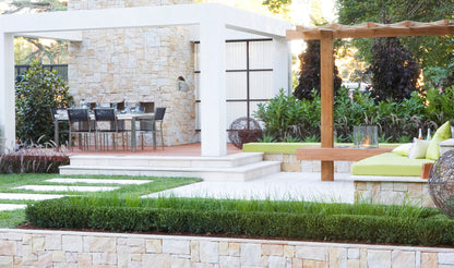 Outdoor patio area with a pergola, chairs, and a stone wall.