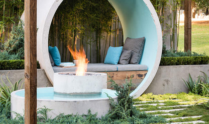 Modern outdoor seating area with fire pit and circular canopy in a garden setting