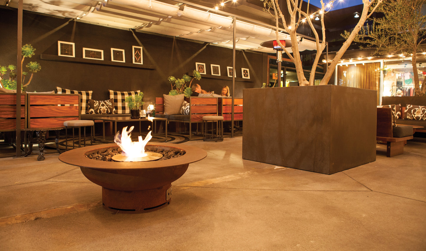 Outdoor patio area with fire pit, tables, and chairs under a covered structure.