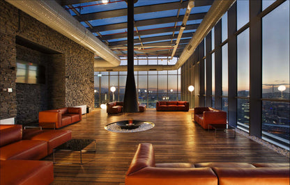 Modern lounge area with red leather furniture and large windows overlooking a cityscape.