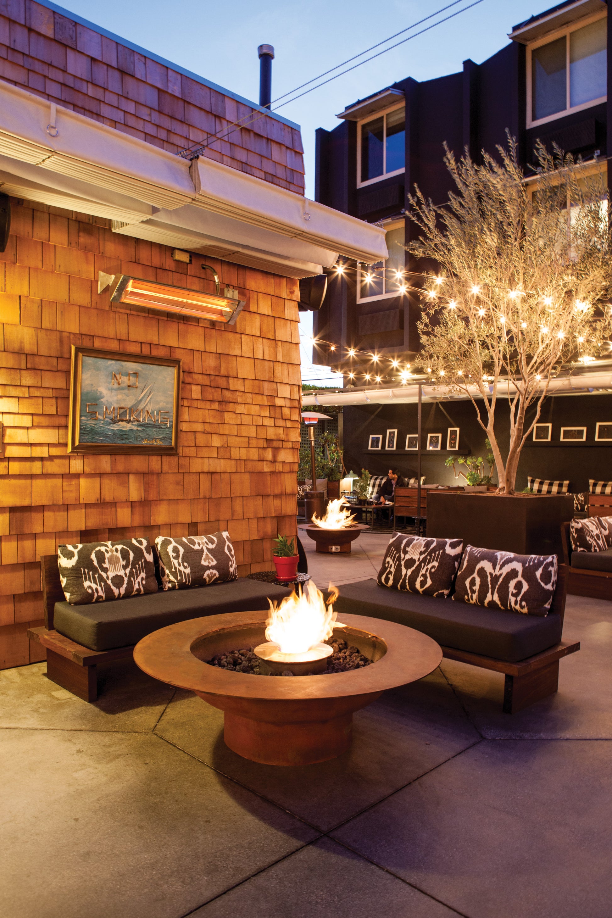 Outdoor patio with fire pit, seating area, and string lights.