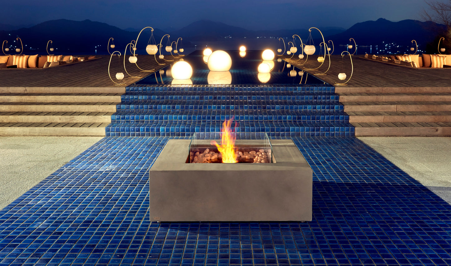 Fire pit on a blue tiled patio with decorative lights and mountains in the background