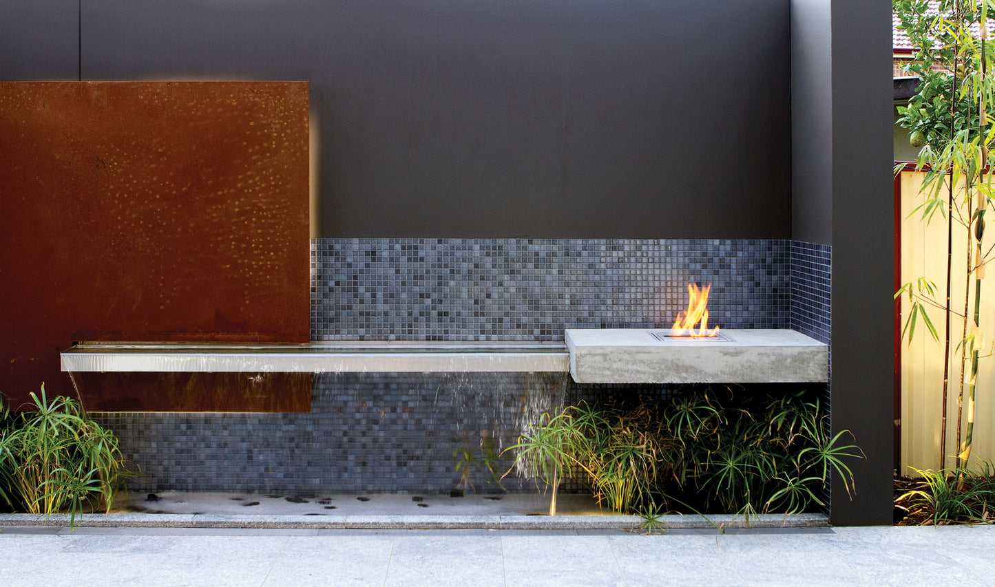 Outdoor setting with a fire pit, bench, and decorative wall.