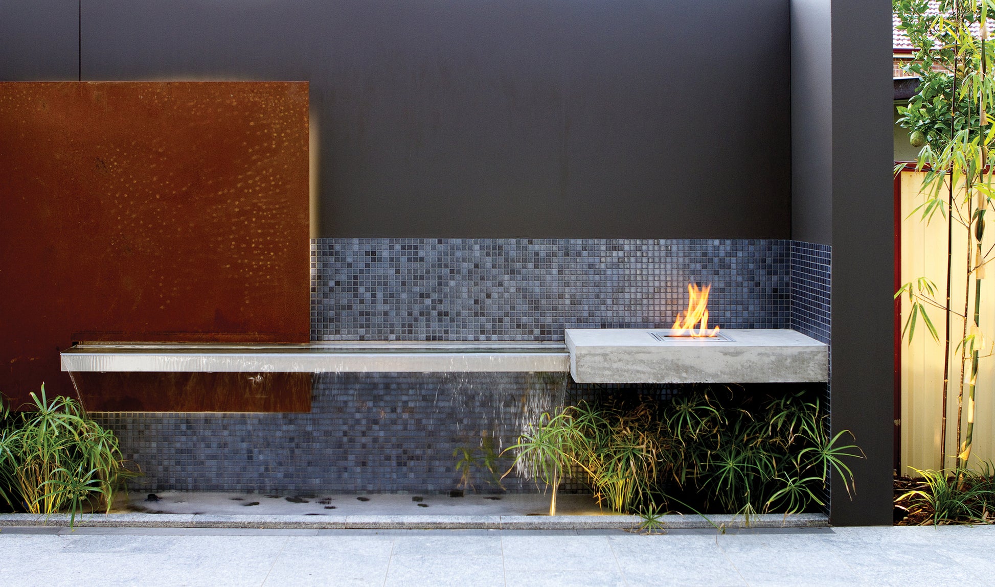 Outdoor setting with a fire pit, bench, and decorative wall.