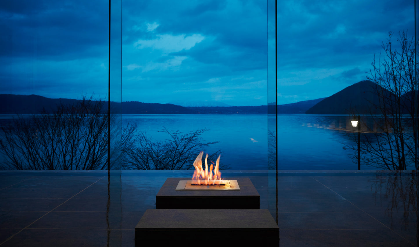 Fire pit by a large window with a view of a lake at night