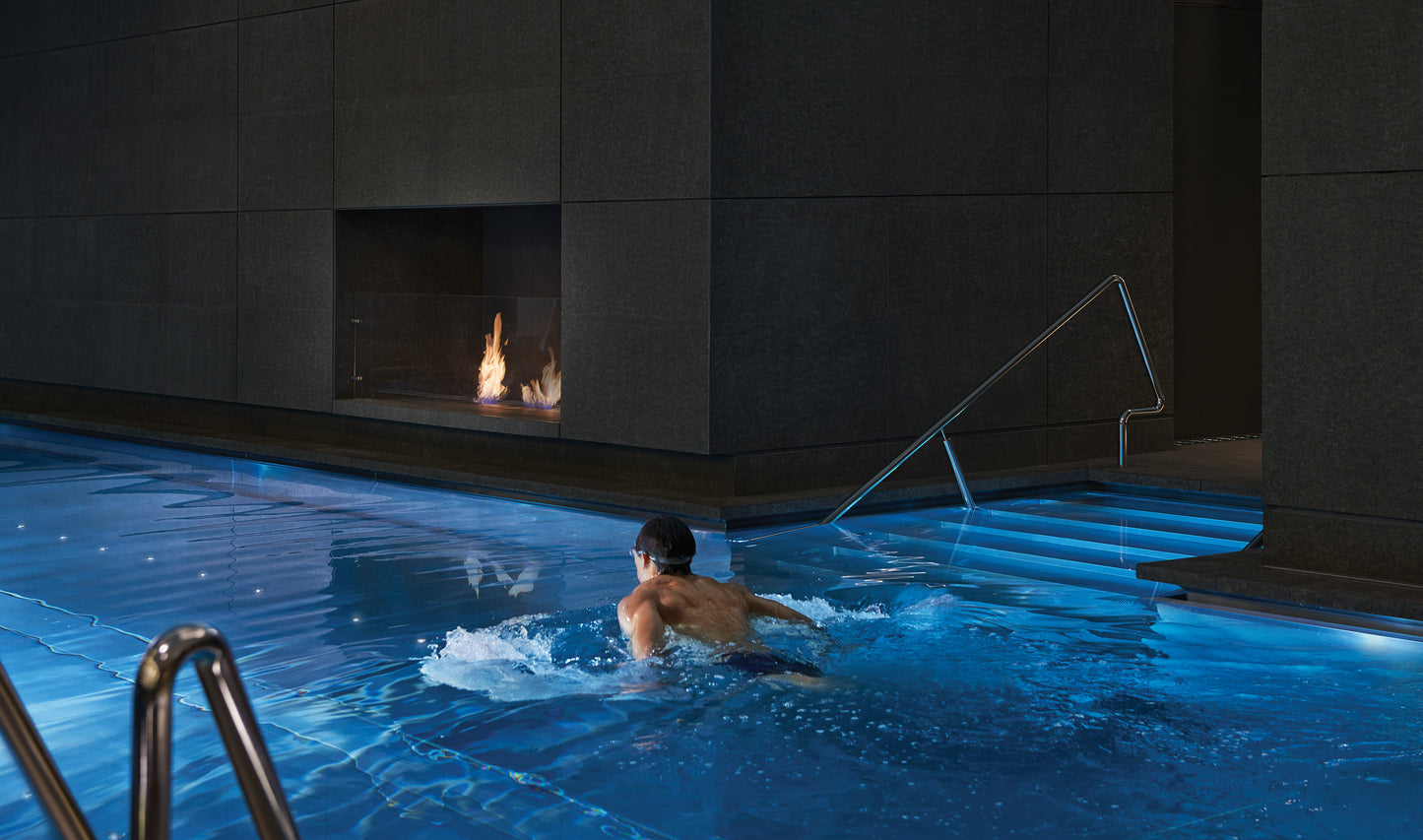 Person swimming in a pool with a fireplace in the background