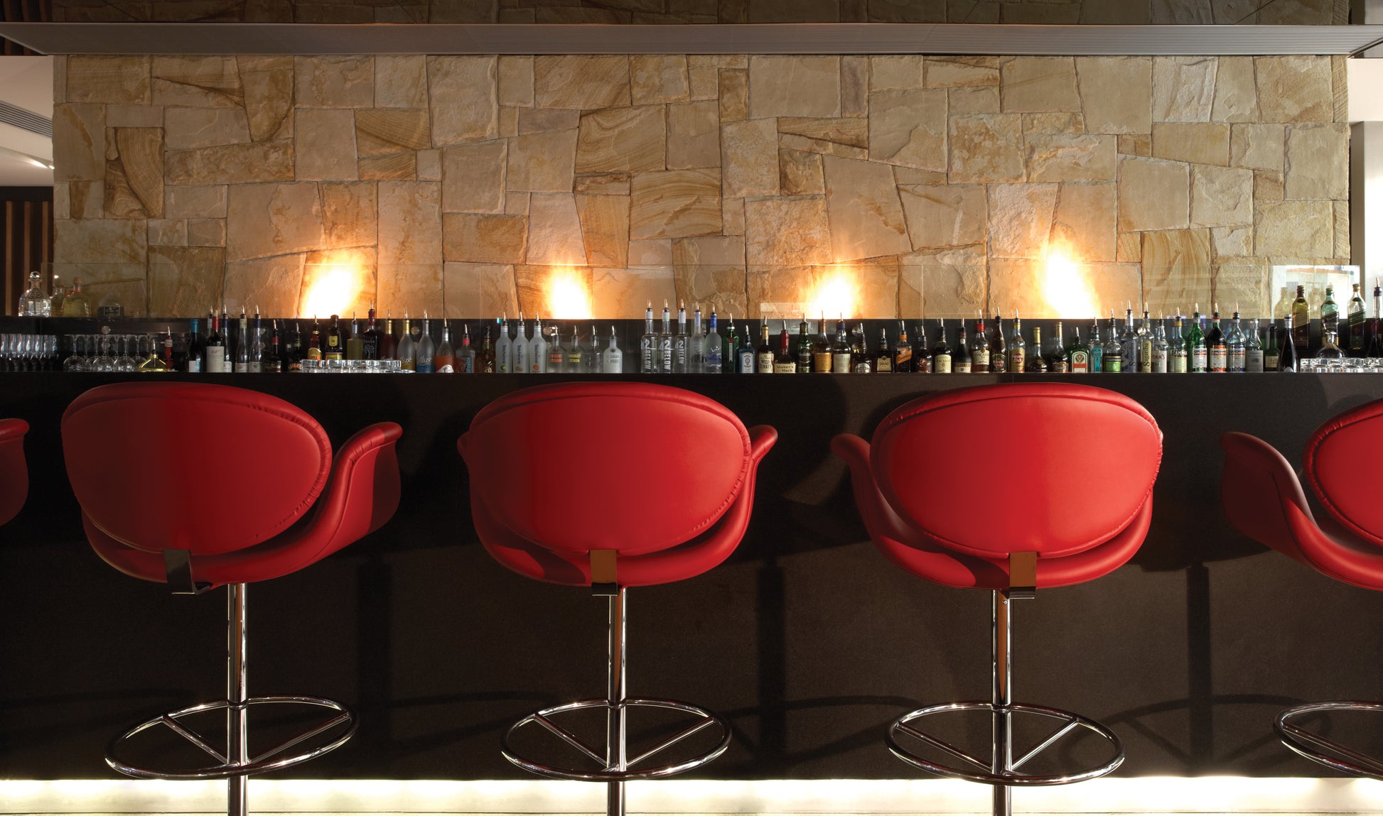 Bar area with red chairs and a stone wall backdrop