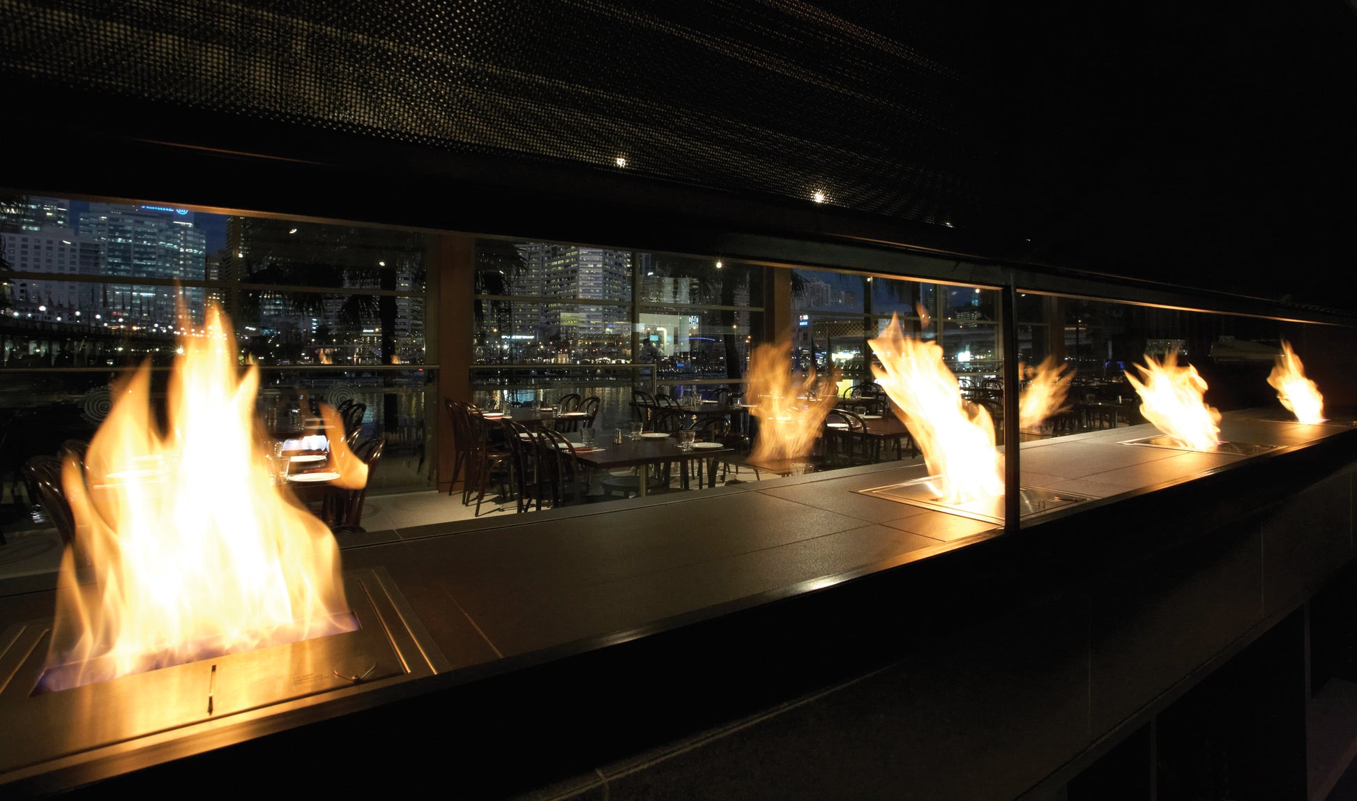 Modern fireplace with flames in a dark room with cityscape view
