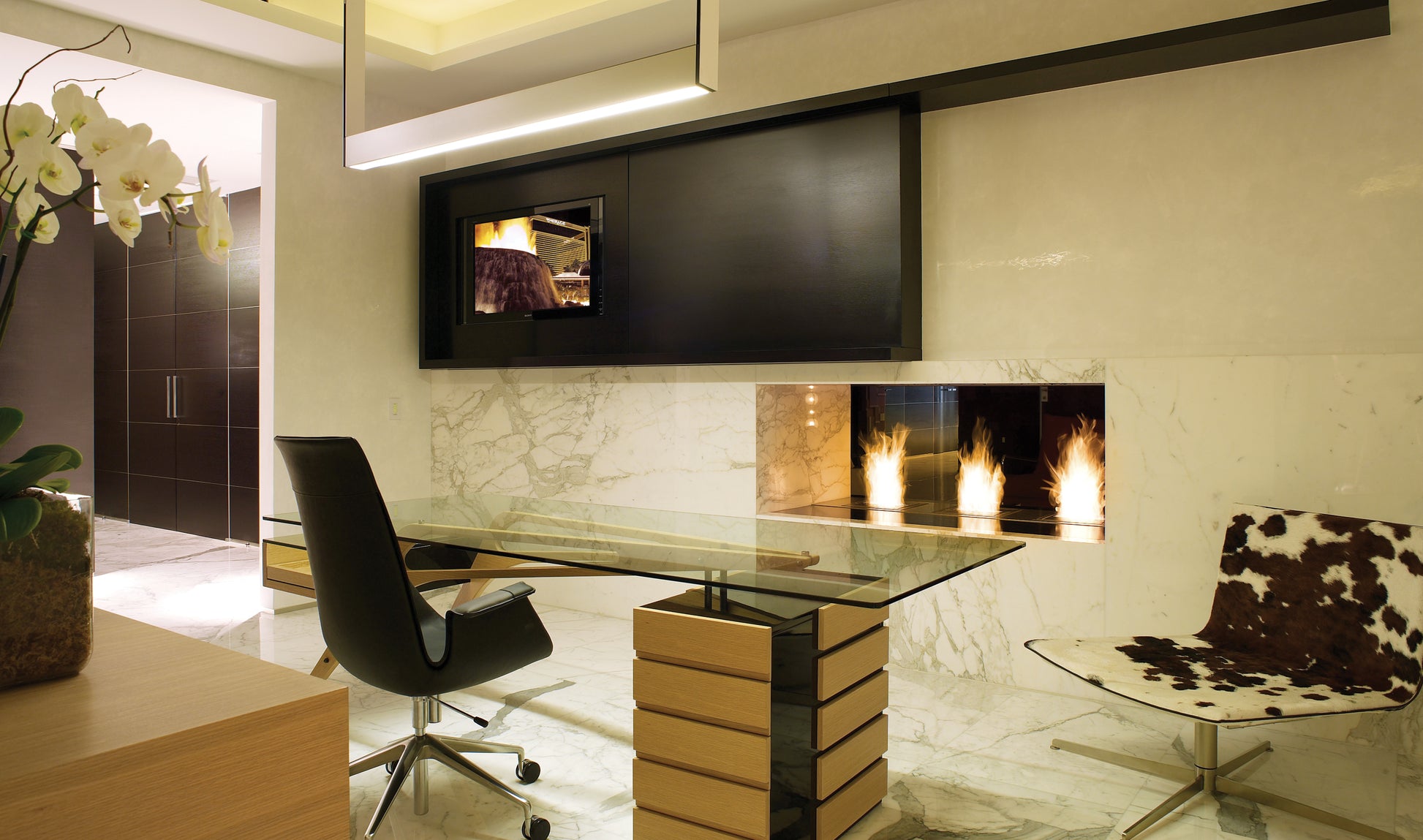 Modern office interior with a desk, chair, and wall-mounted TV.