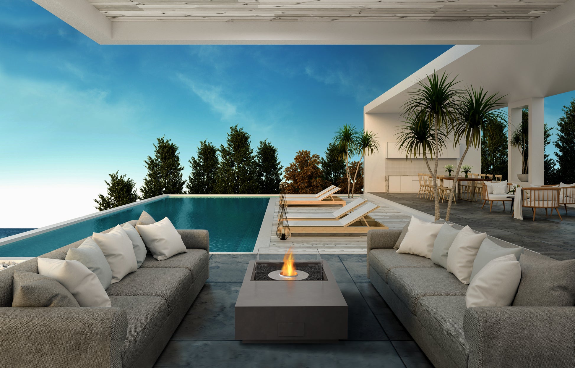 Modern outdoor patio with gray sofas, fire pit, and pool view