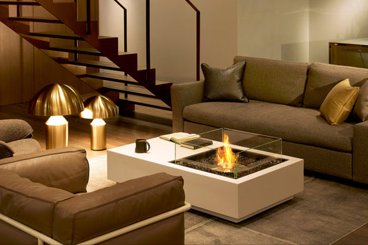 Modern living room with a staircase, sofa, and coffee table with a firepit.