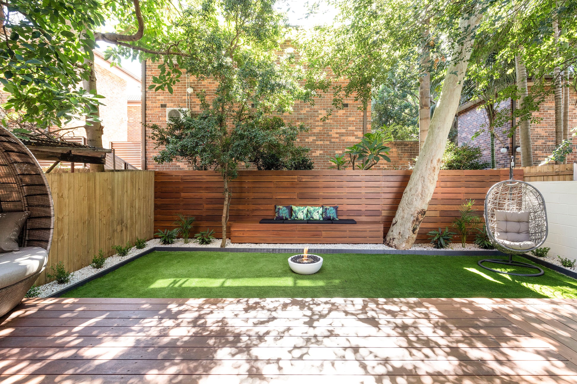 Modern backyard with artificial grass, a fire pit, and outdoor furniture.