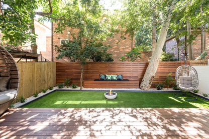 Modern backyard with artificial grass, a fire pit, and outdoor furniture.