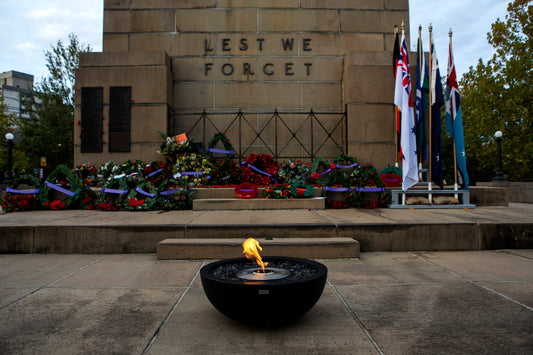 Memorial with wreaths, flags, and a eternal flame in front