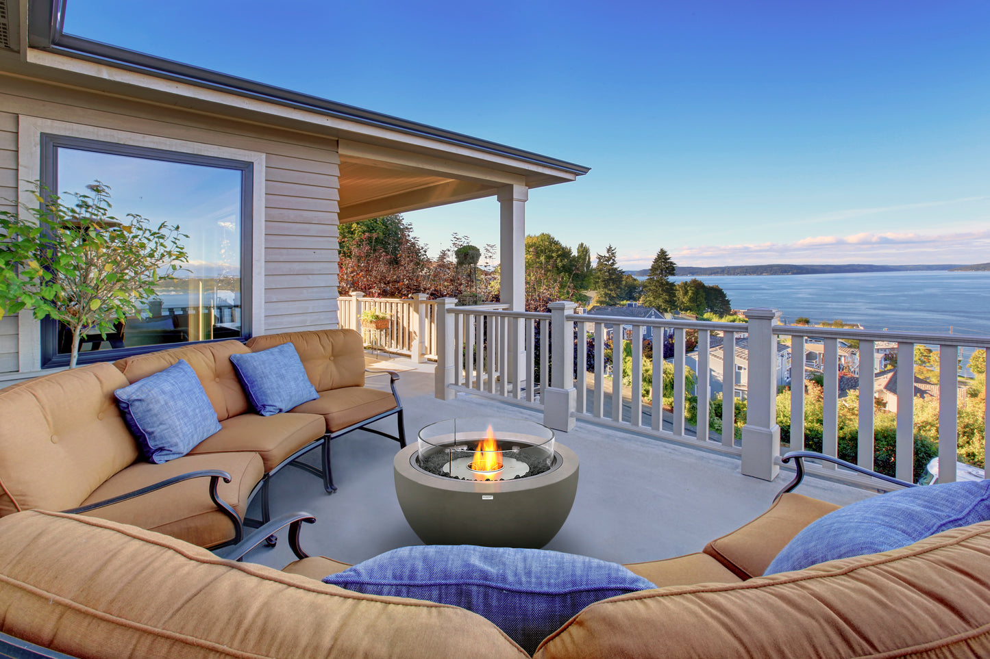Outdoor patio with beige sofa, fire pit, and ocean view