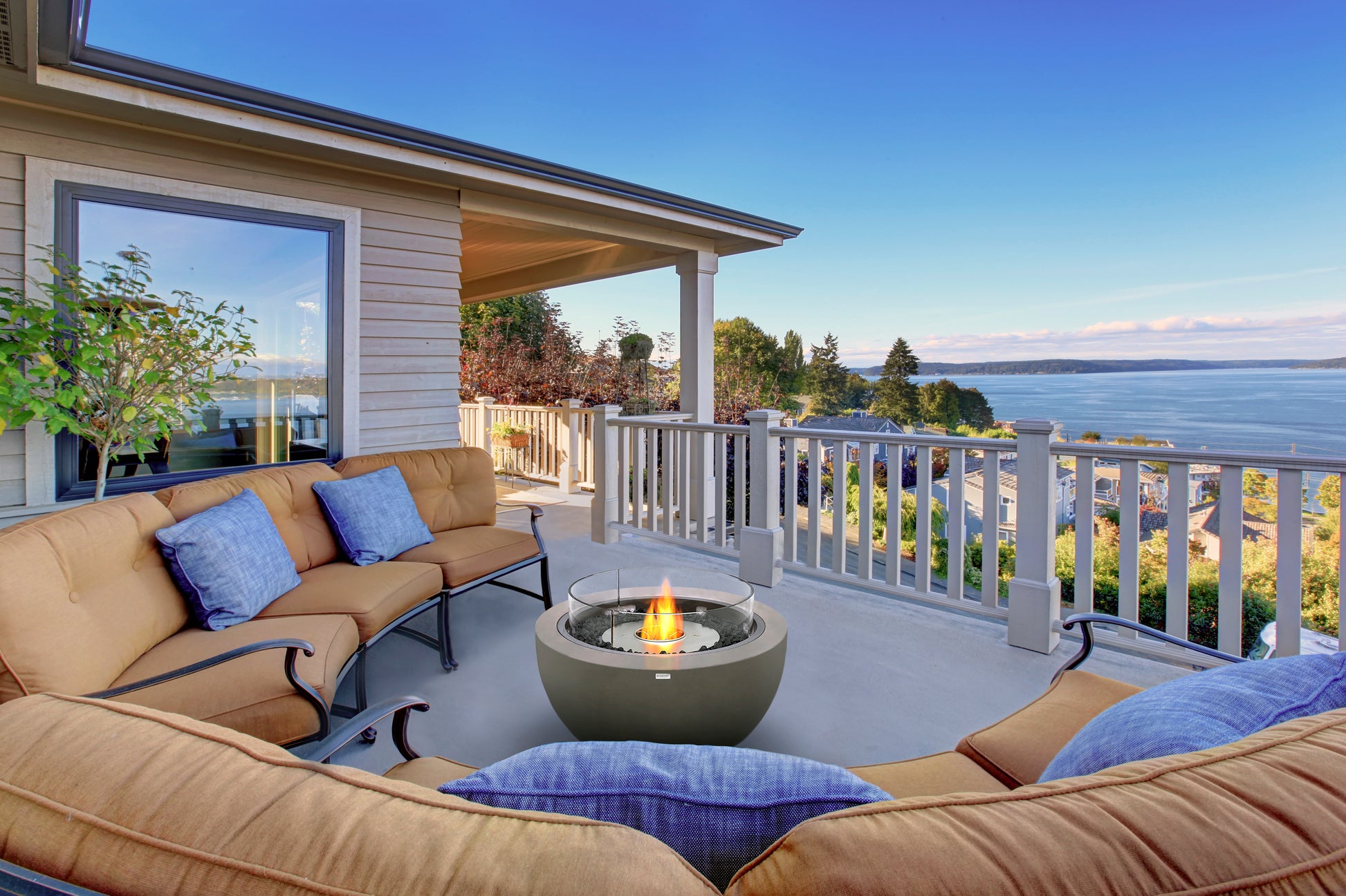 Outdoor patio with beige sofa, fire pit, and ocean view