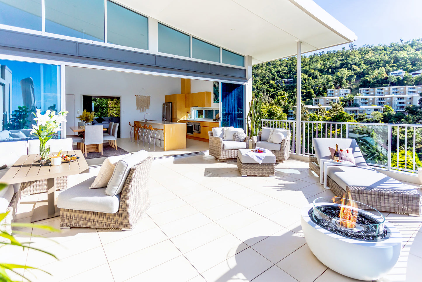 Modern patio with outdoor furniture and fire pit, overlooking a scenic view.