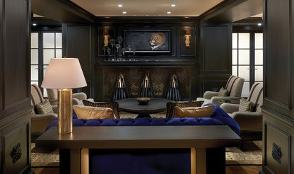 Luxury lounge with dark wood paneling, plush seating, and a mounted television displaying a lion.