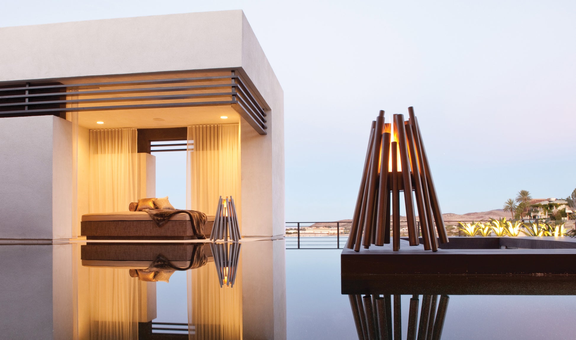 Modern outdoor setting with a bed and a lamp near a pool at dusk.