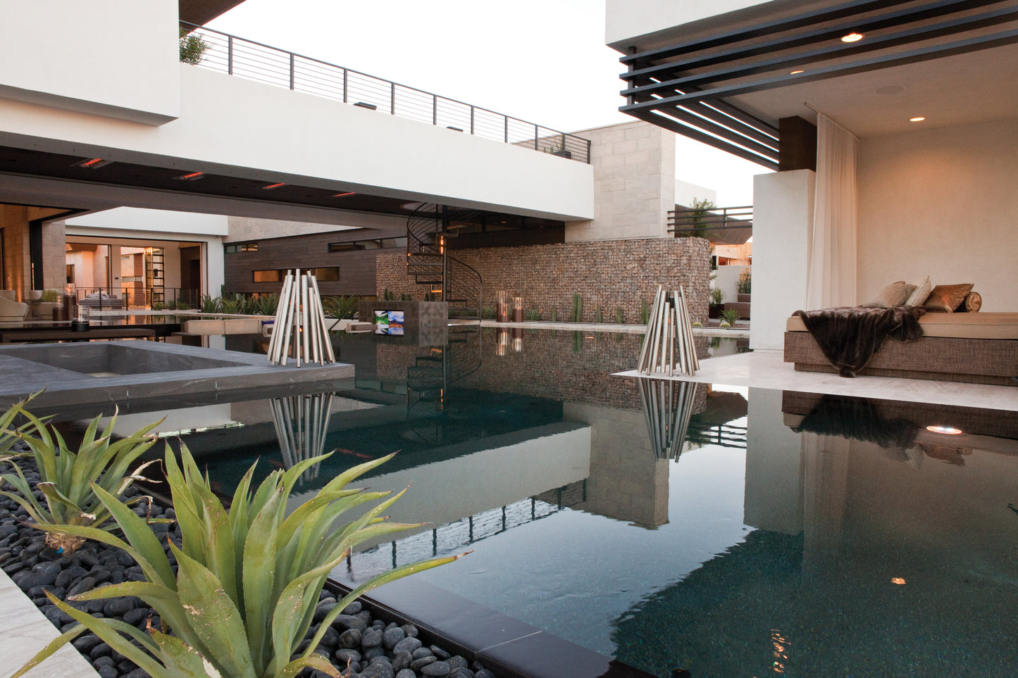 Modern indoor pool area with a couch and decorative elements.
